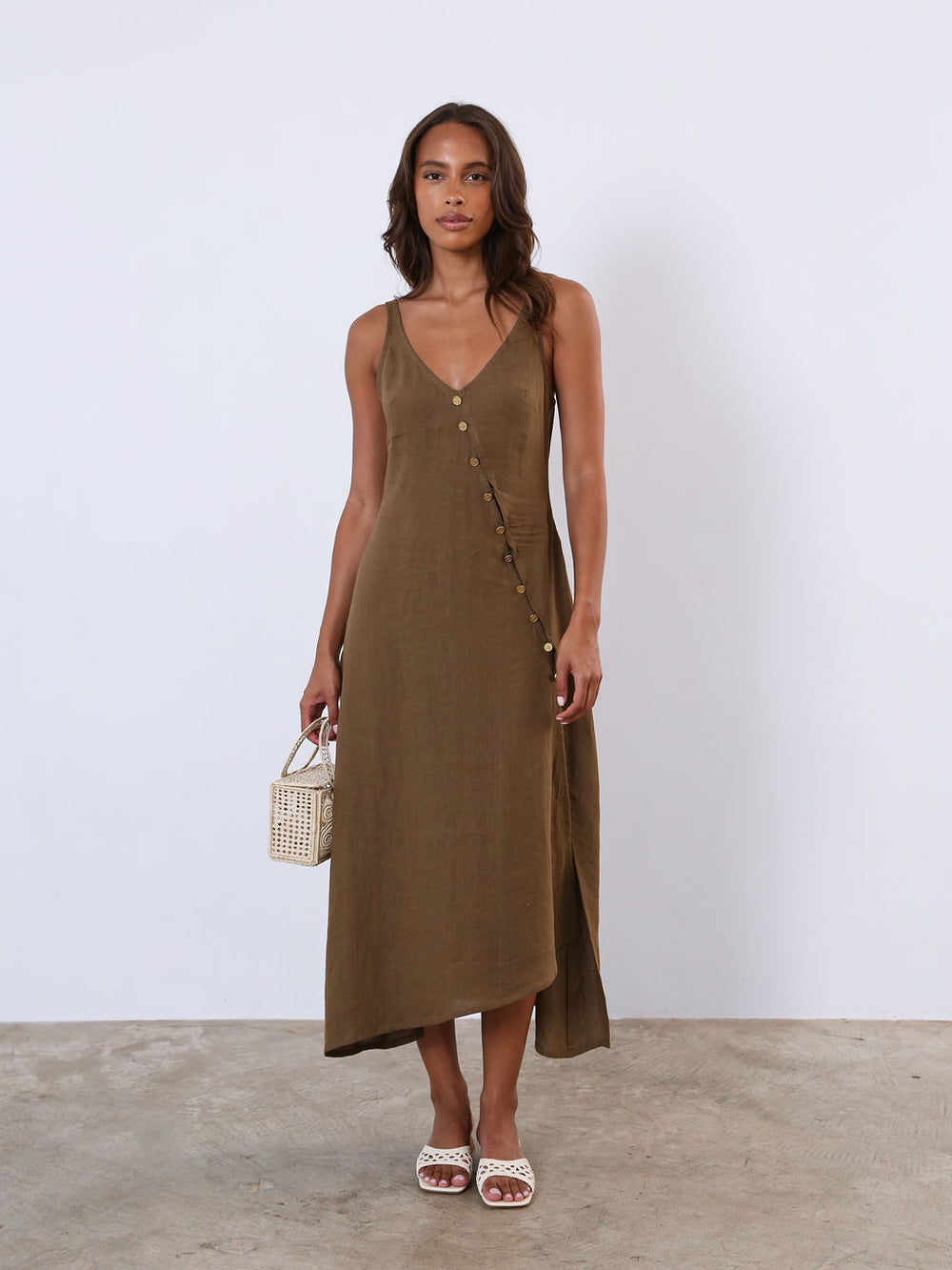 woman in brown dress standing against white wall